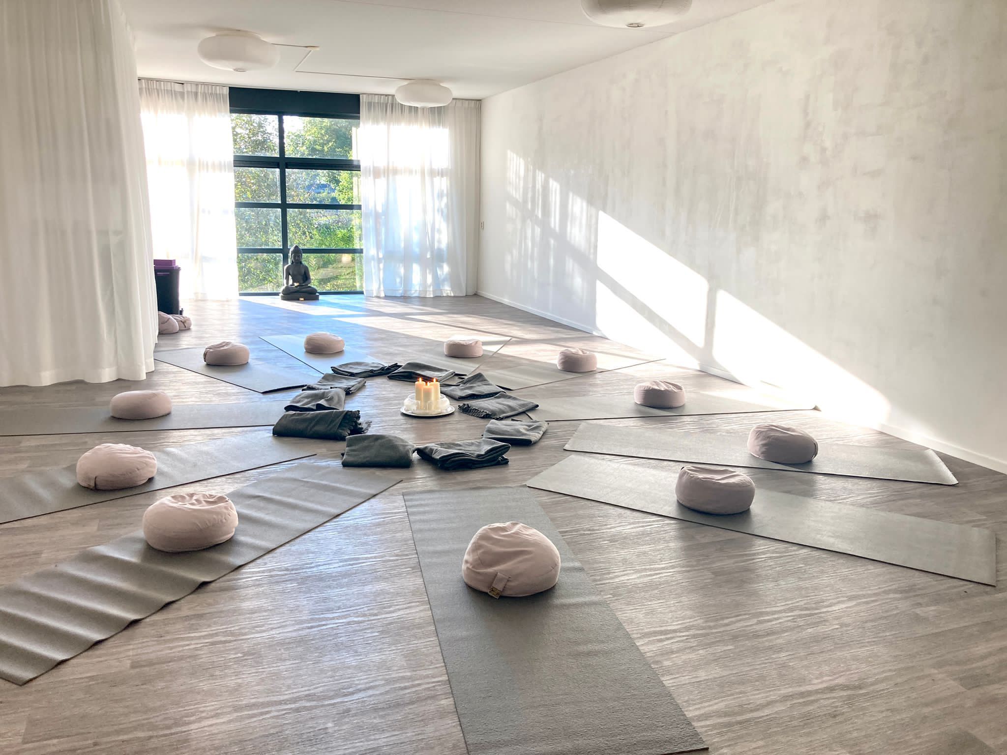 De yogastudio met matten in mandala-opstelling rond kaarsen